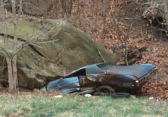 A car underneat a very large rock