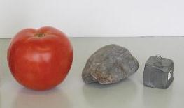 A large tomato, a medium-sized rock, and a small lead cube